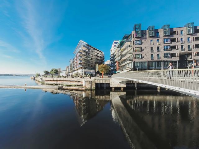 Moderna hus och en gångbro vid vattnet på Aker Brygge i Oslo