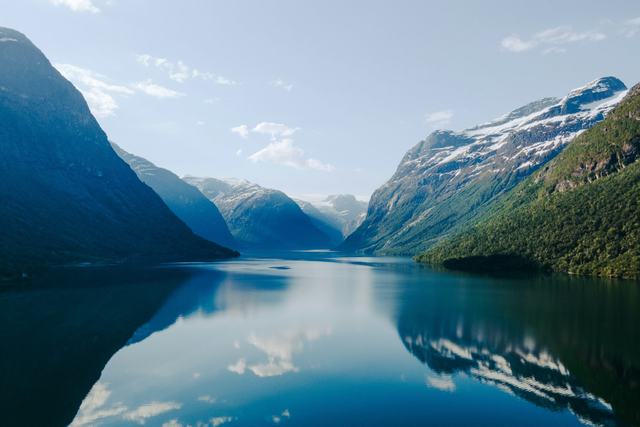 Blank fjord omgiven av branta, delvis snöklädda berg